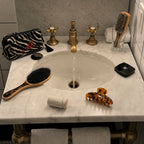 Bathroom sink with various items including a brush, hair clip, and toiletries.