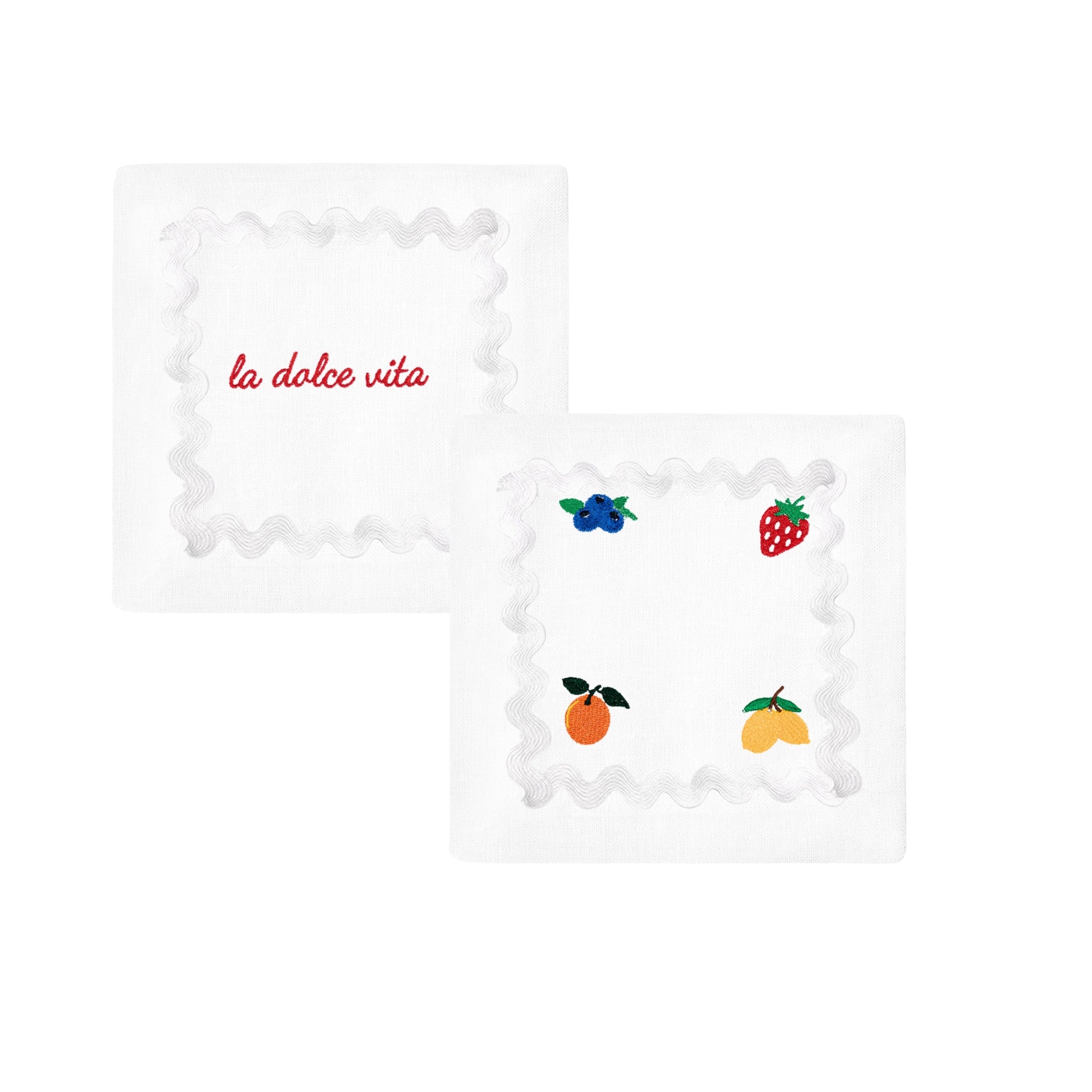 Embroidered white napkins with fruit designs and 'la dolce vita' text, perfect for stylish dining.