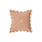 Personalized blush pink pillow with scalloped edges and embroidered 'A' monogram.
