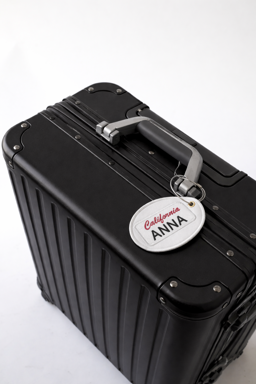Black hard-shell suitcase with silver handle and personalized tag, perfect for travel and durability.