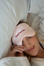 Pink satin sleep mask with 'Stayed out late' embroidery, perfect for comfort and style during sleep.