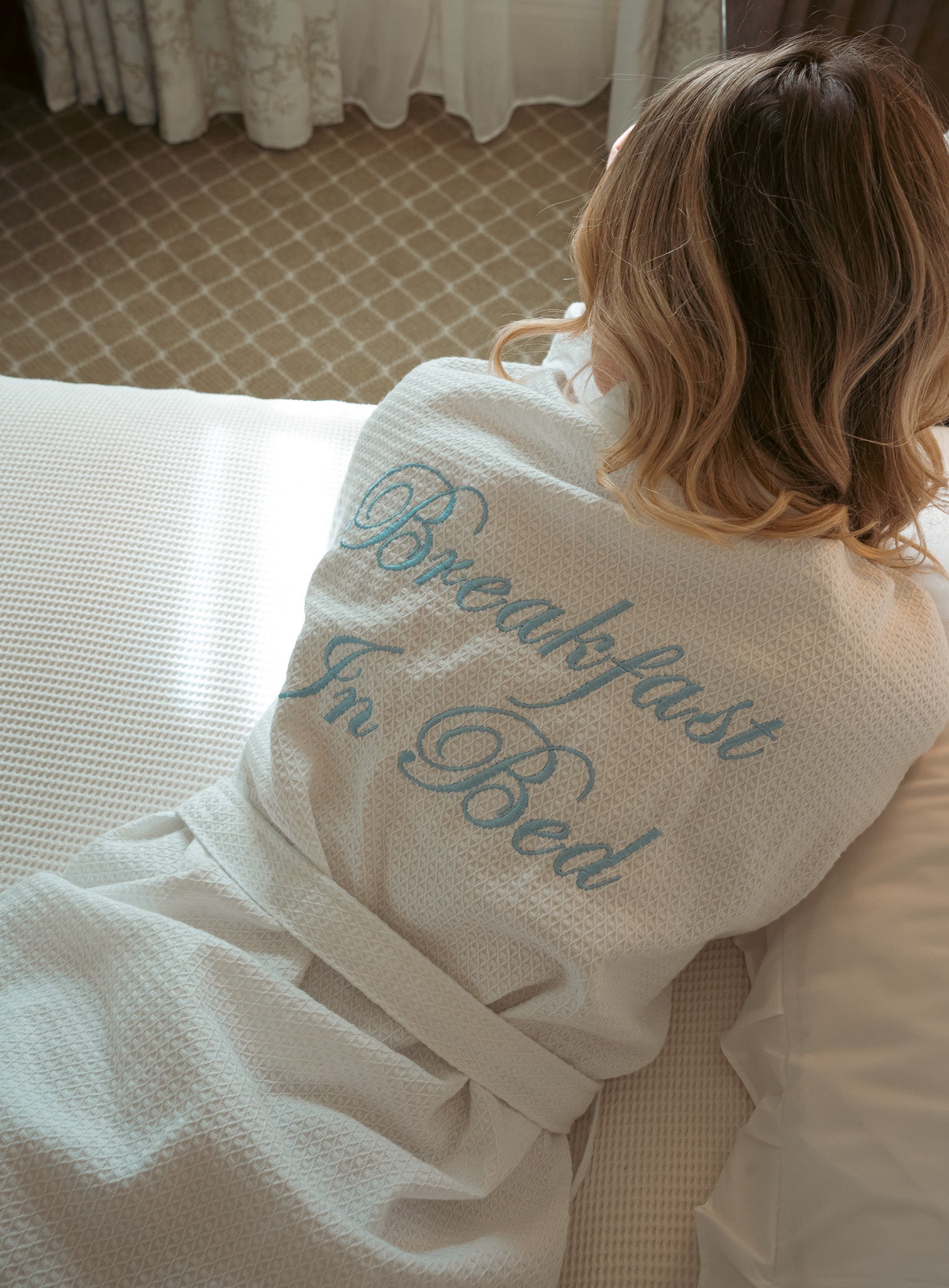 Cozy white waffle bathrobe featuring 'Breakfast In Bed' embroidery, perfect for lounging.