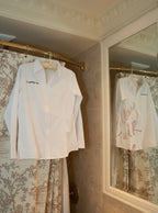 White button-up shirt with 'It's giving wife' text, perfect for stylish casual or bridal wear.