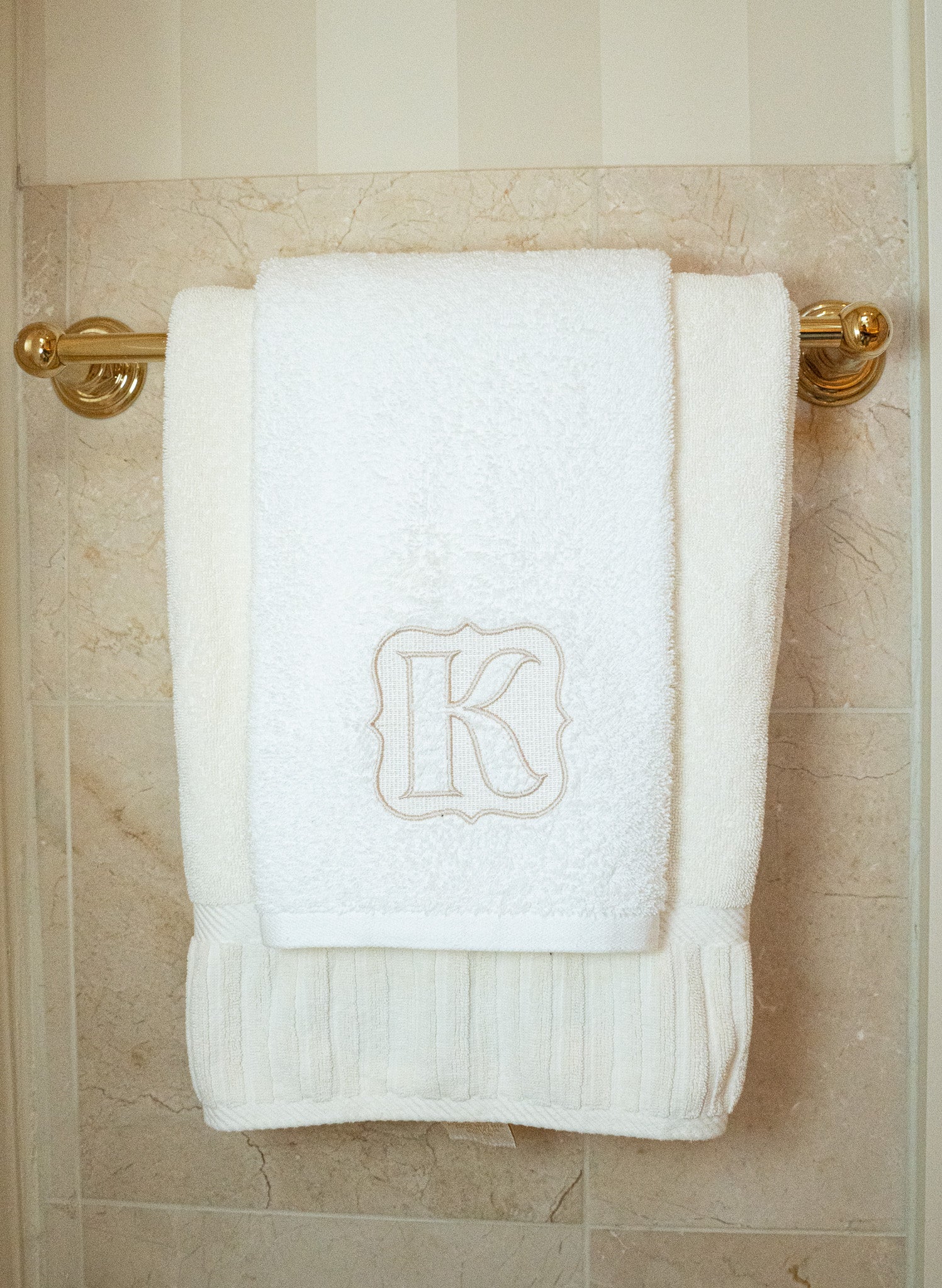 Soft white cotton bath towel with embroidered letter 'K', perfect for luxury bathroom decor.