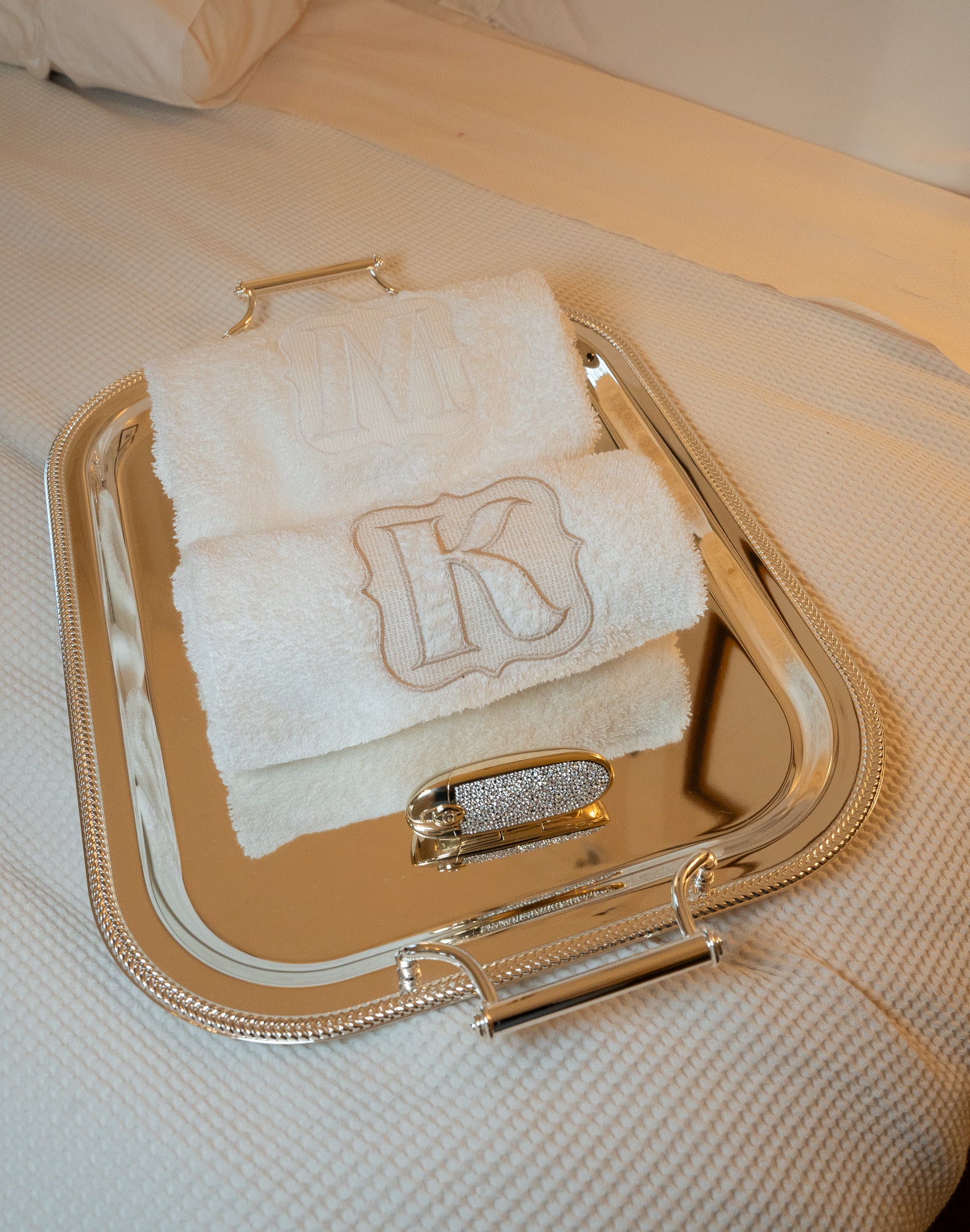 Luxury white bath towels with monograms 'M' and 'K' on a silver serving tray, perfect for elegant decor.
