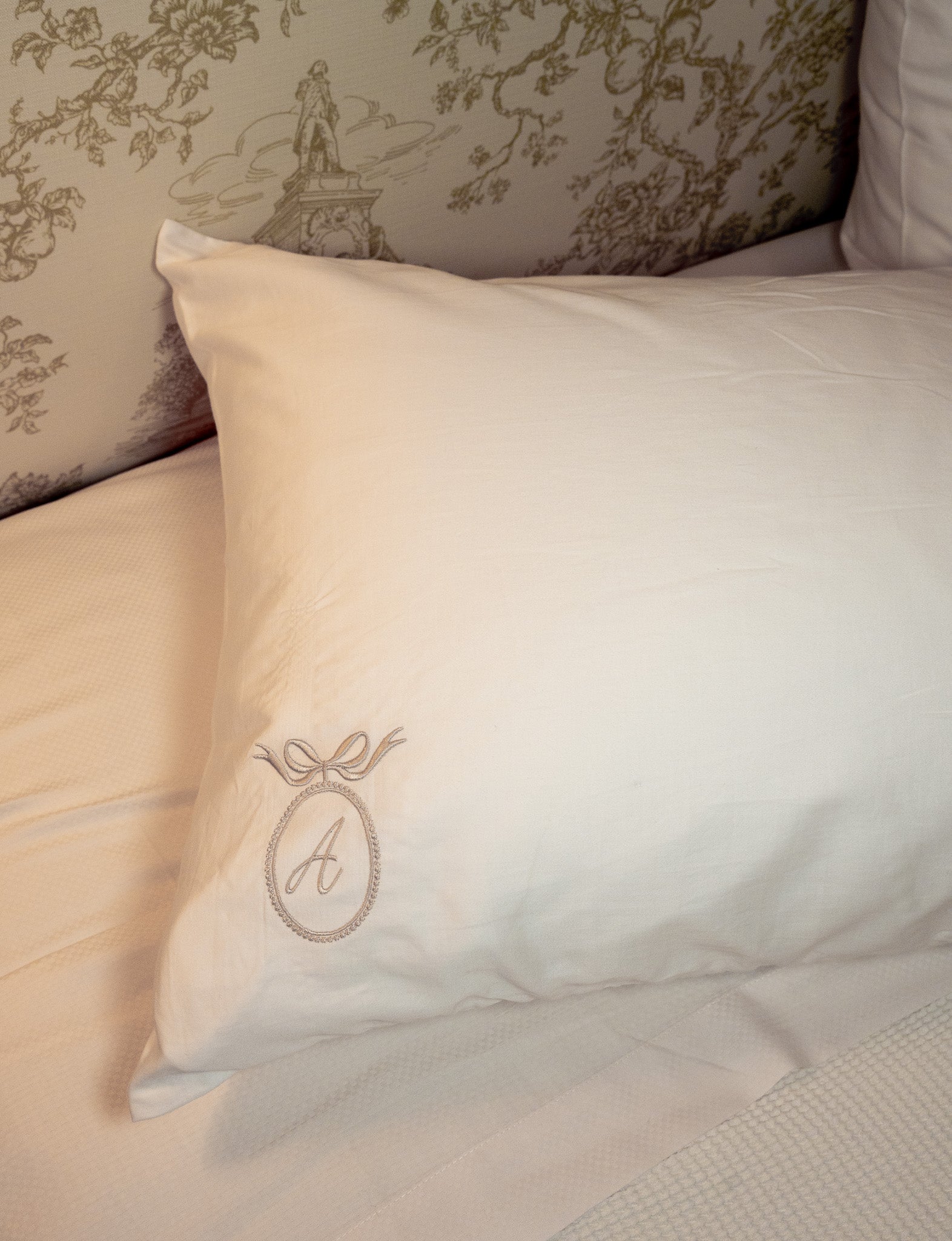 Elegant white pillow with embroidered initial 'A', perfect for chic bedroom decor.
