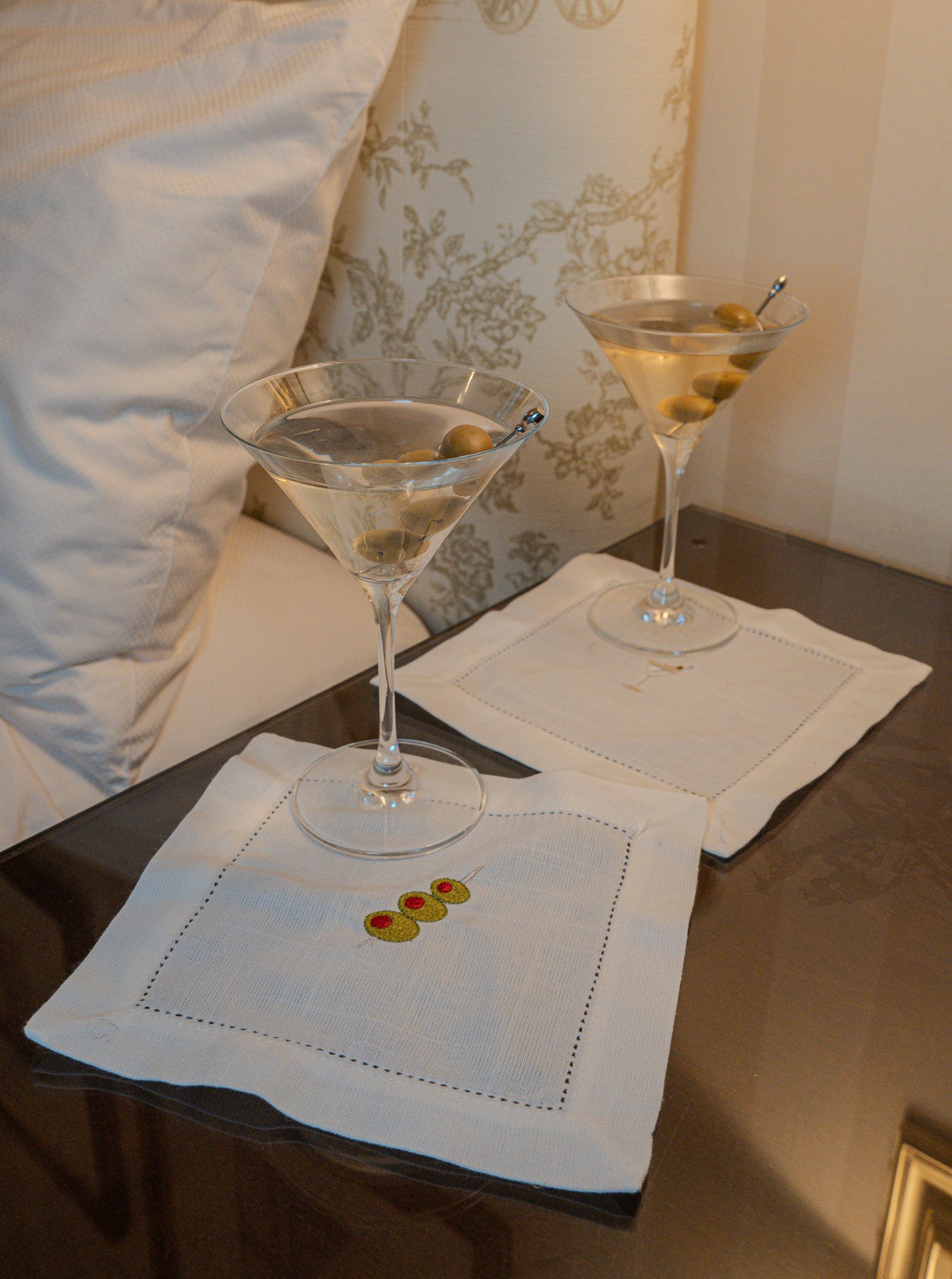 Elegant embroidered cocktail napkins with olives and martinis on a table, perfect for upscale gatherings.