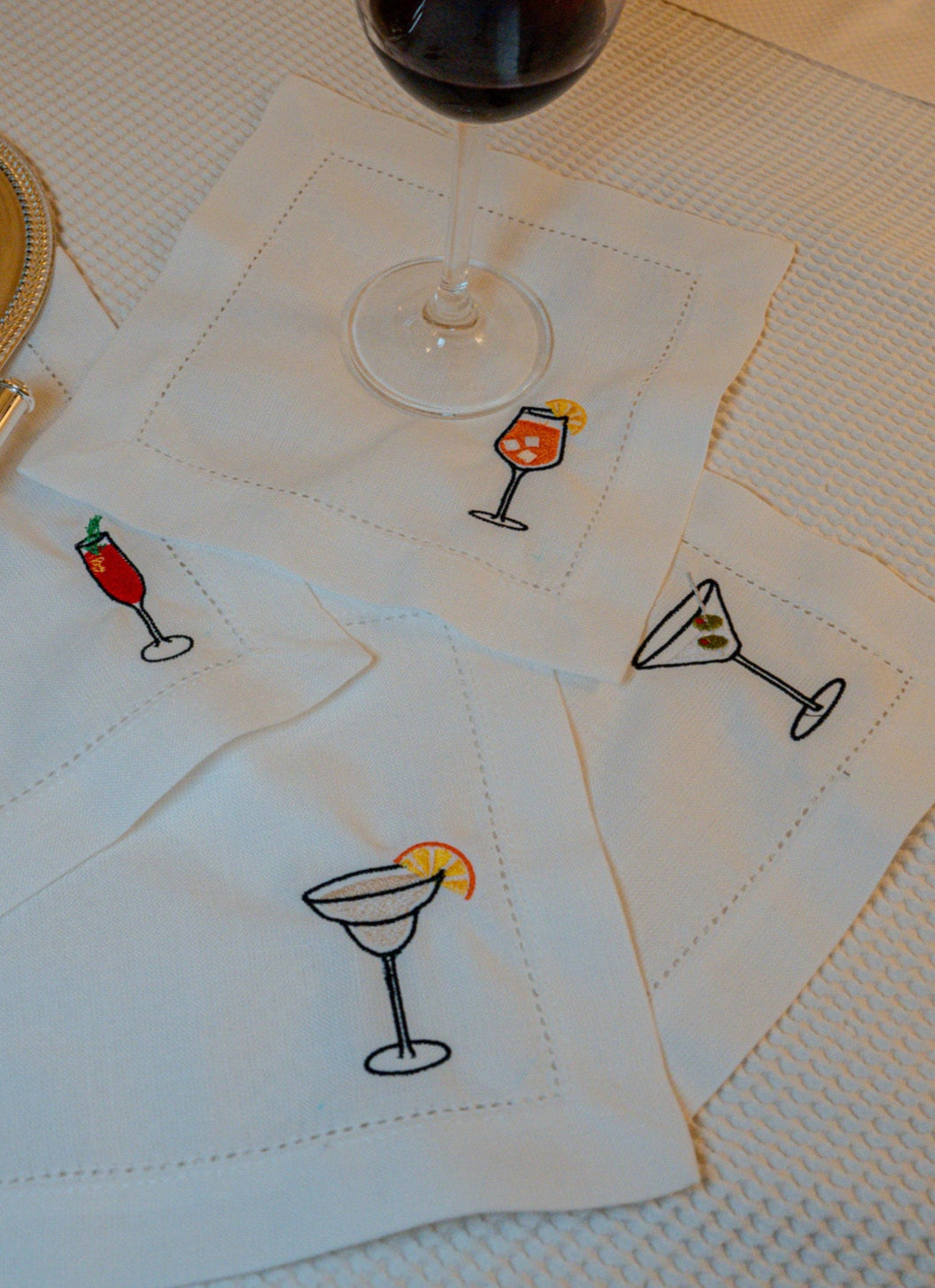Embroidered cocktail-themed cotton napkins in white, featuring colorful drink designs.