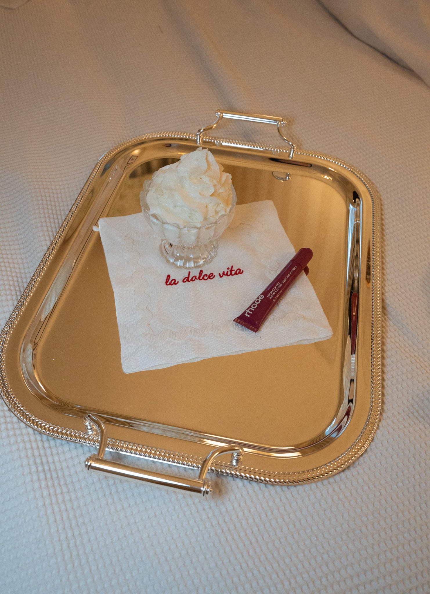 Elegant silver serving tray with whipped cream and a decorative napkin, perfect for desserts.