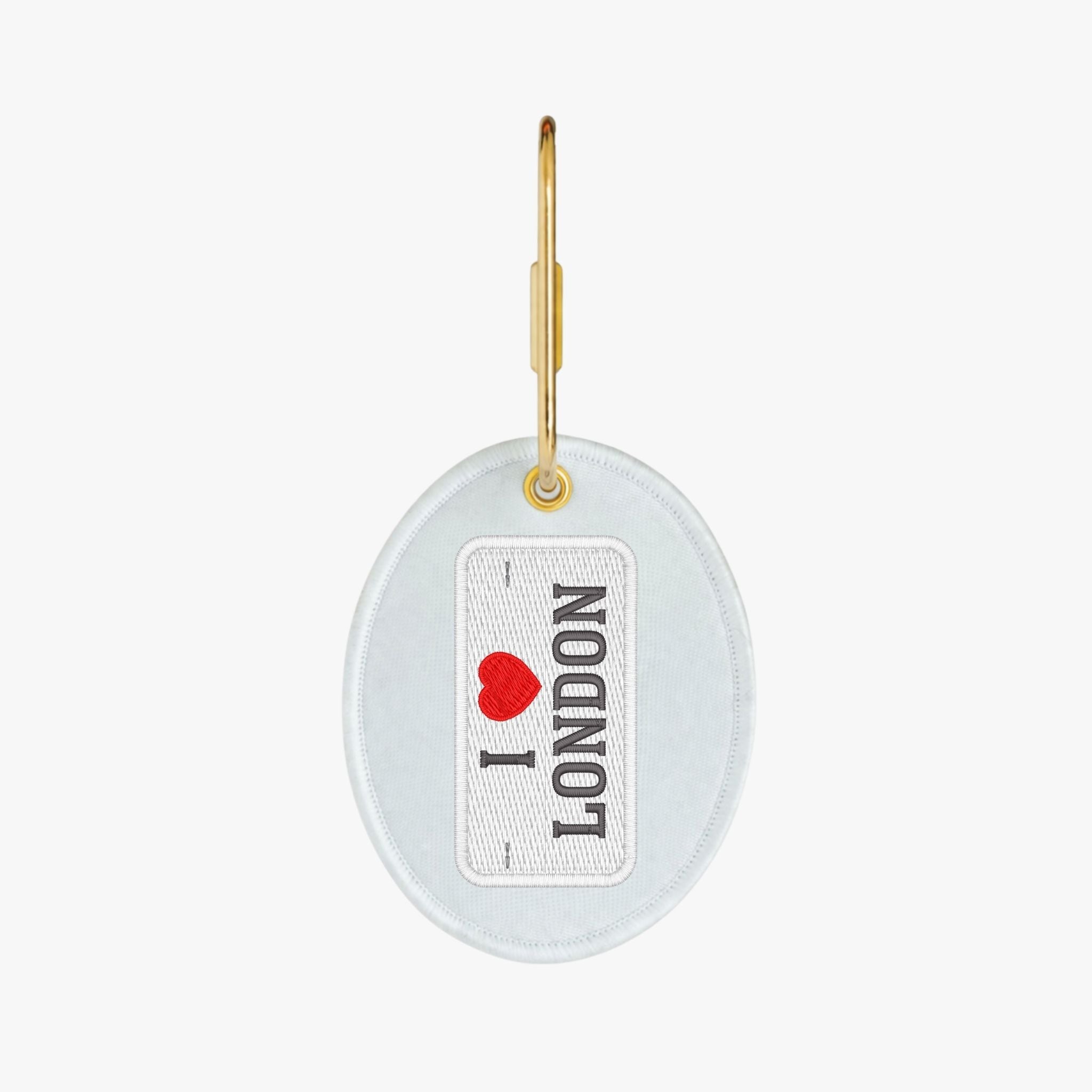 I Love London keychain, oval shape, white fabric with red heart and black lettering, gold metal attachment.