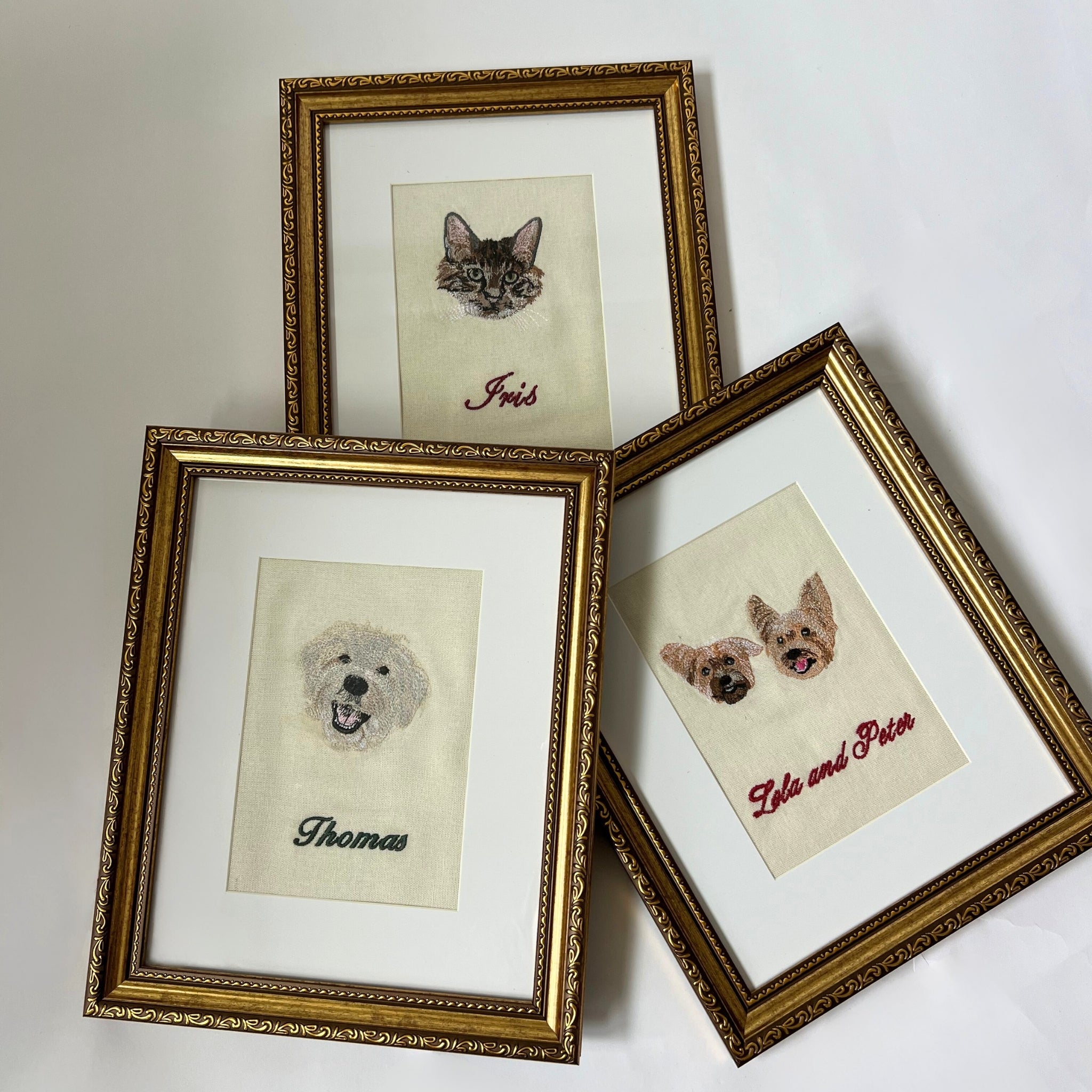 Personalized pet portraits in gold frames, featuring a cat, dog, and two dogs, intricate embroidery on fabric.