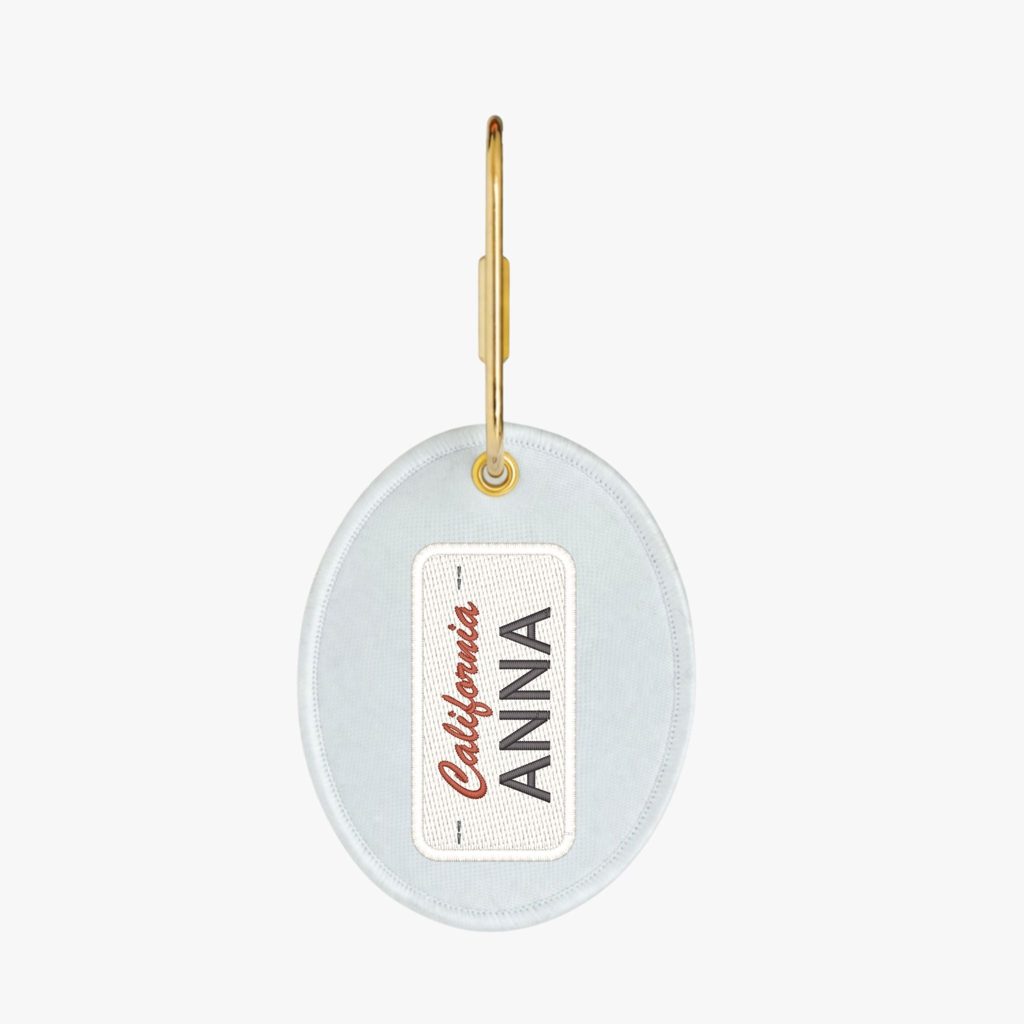 Personalized oval keychain in light blue with gold hardware and customizable name tag.