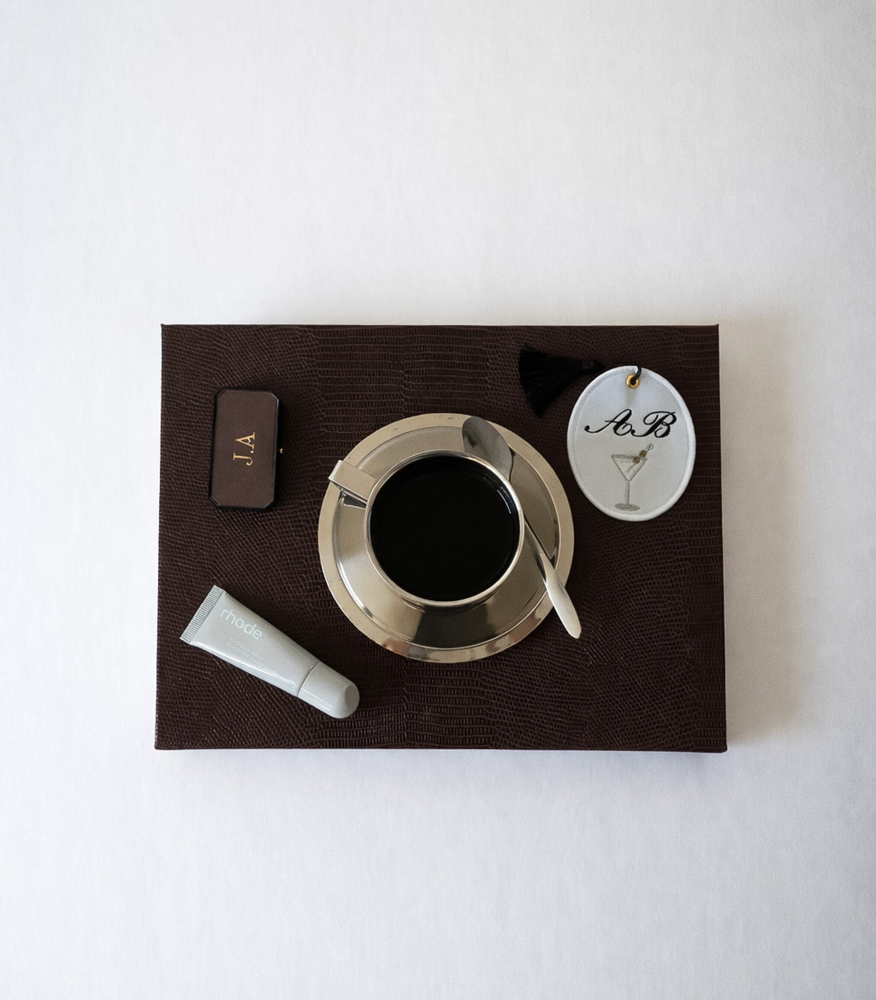 Stylish brown textured tray with coffee, a skincare product, and personalized tags.