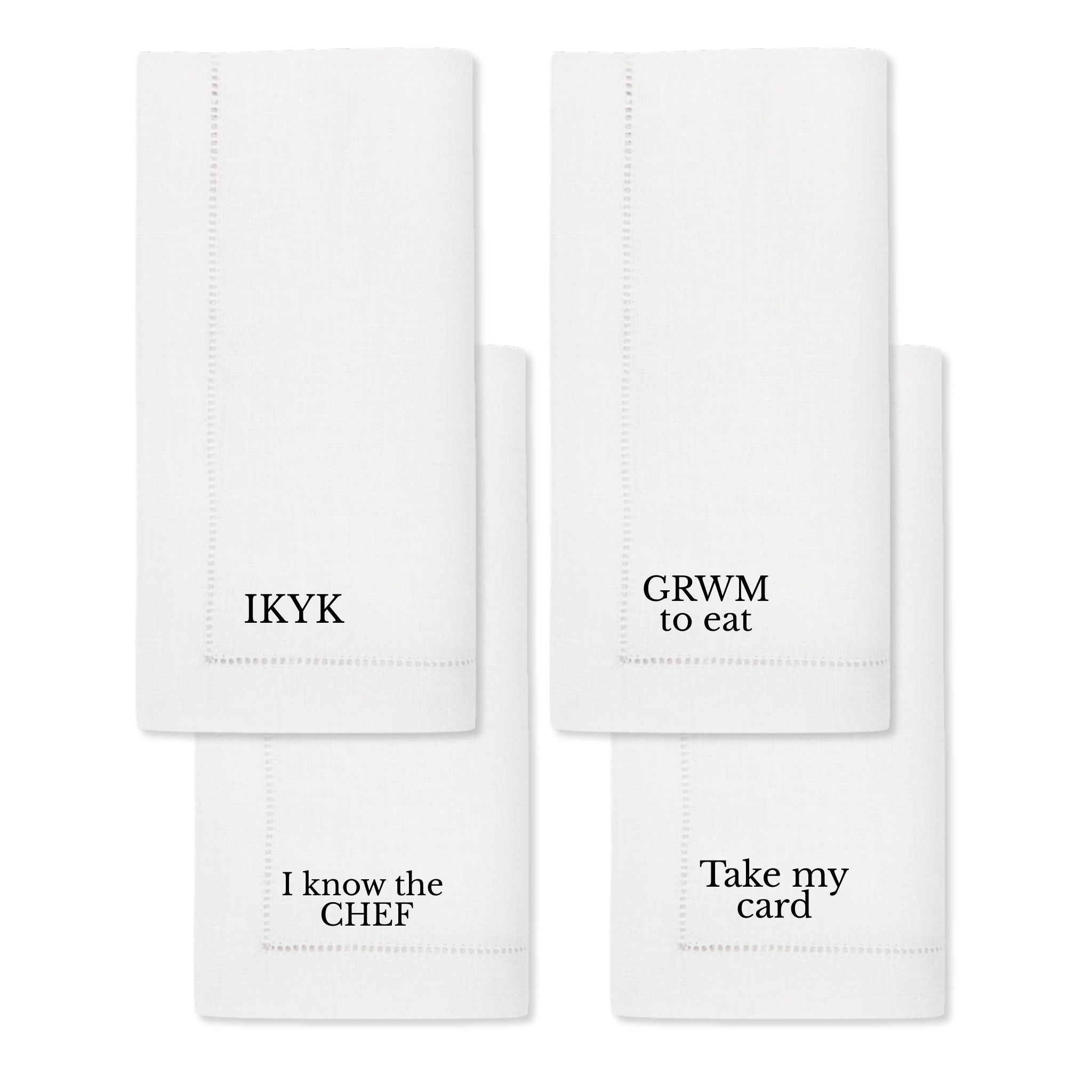 Set of four white cotton napkins with humorous quotes: IKYK, GRWM to eat, I know the CHEF, Take my card.