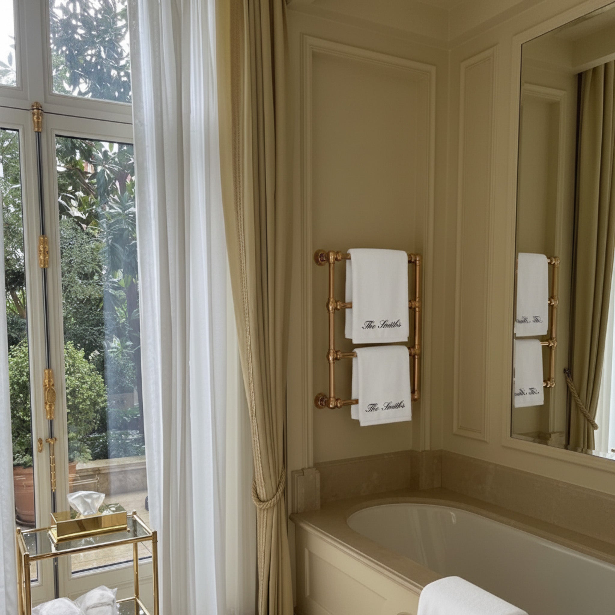Luxurious bathroom with gold towel rack, white towels, marble countertop, and elegant curtains.