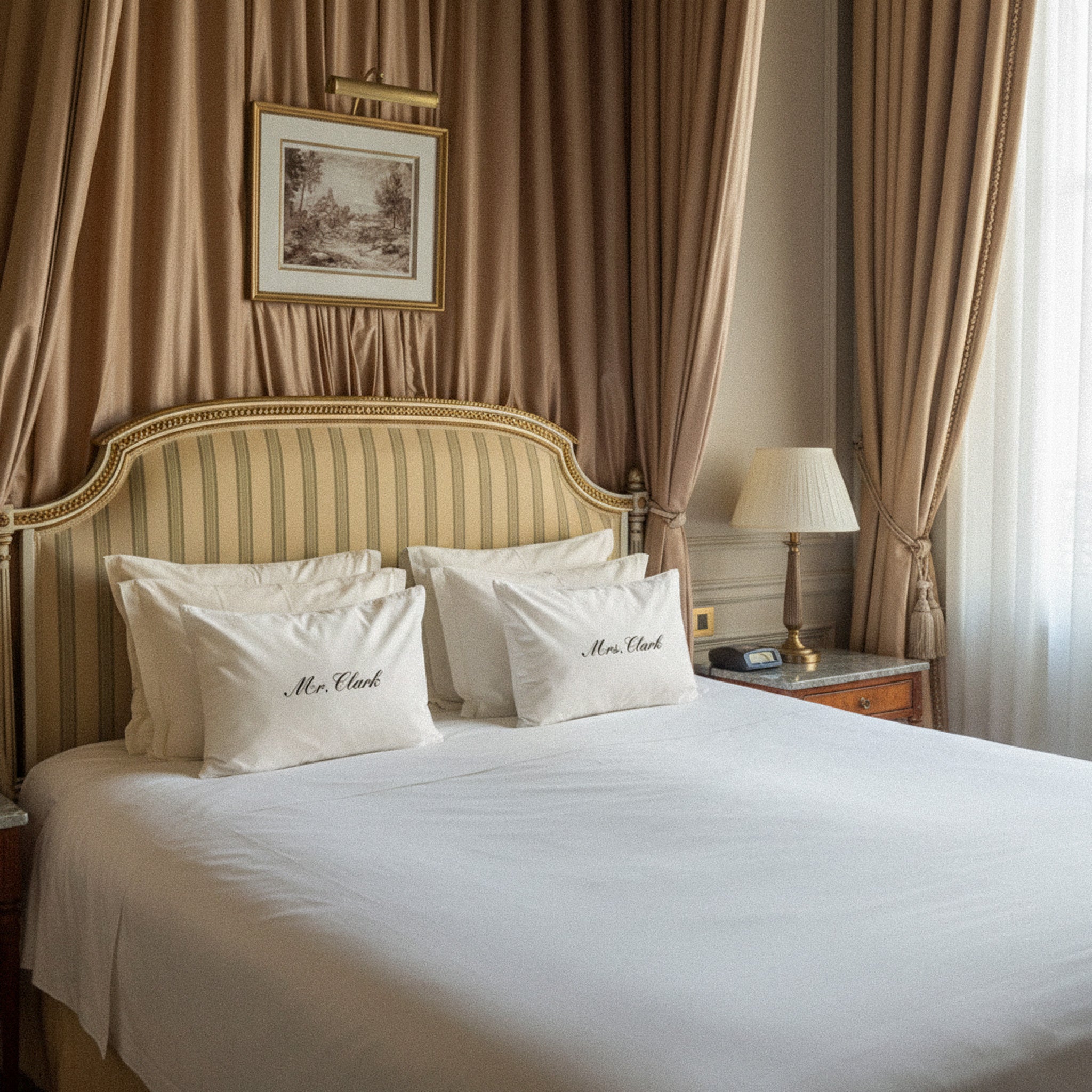Elegant king bed with personalized white pillows, gold-striped headboard, and soft bedding in a luxurious room.