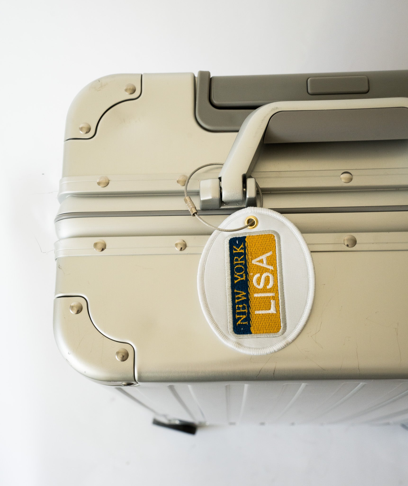 Sleek silver luggage with a New York tag, durable aluminum shell, perfect for stylish travel.