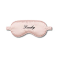 Pink sleep mask with 'Lucky' text on a white background