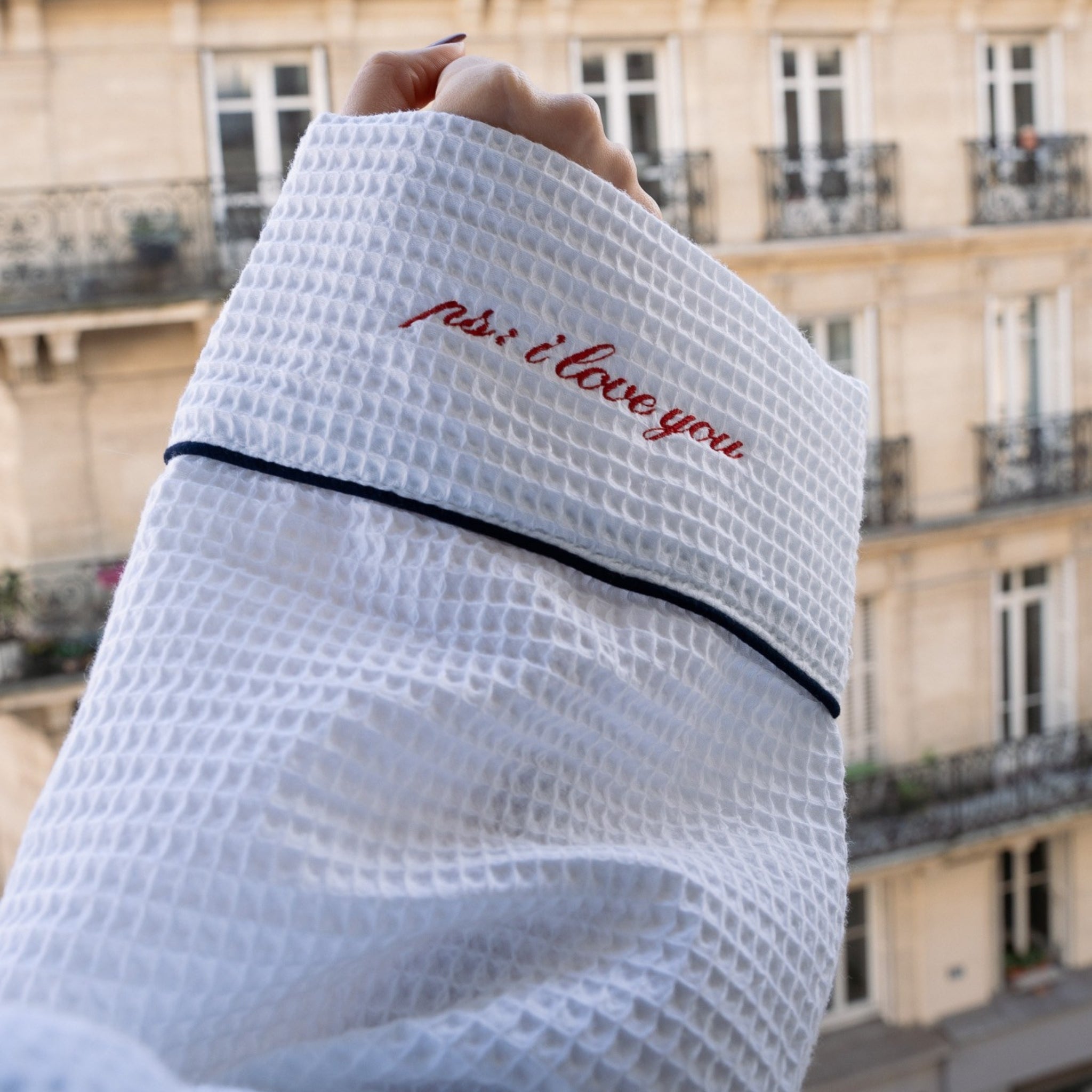 White waffle robe with 'just i love you' text held in front of a building.