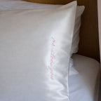 White pillow with 'I'm home' embroidery on a bed.